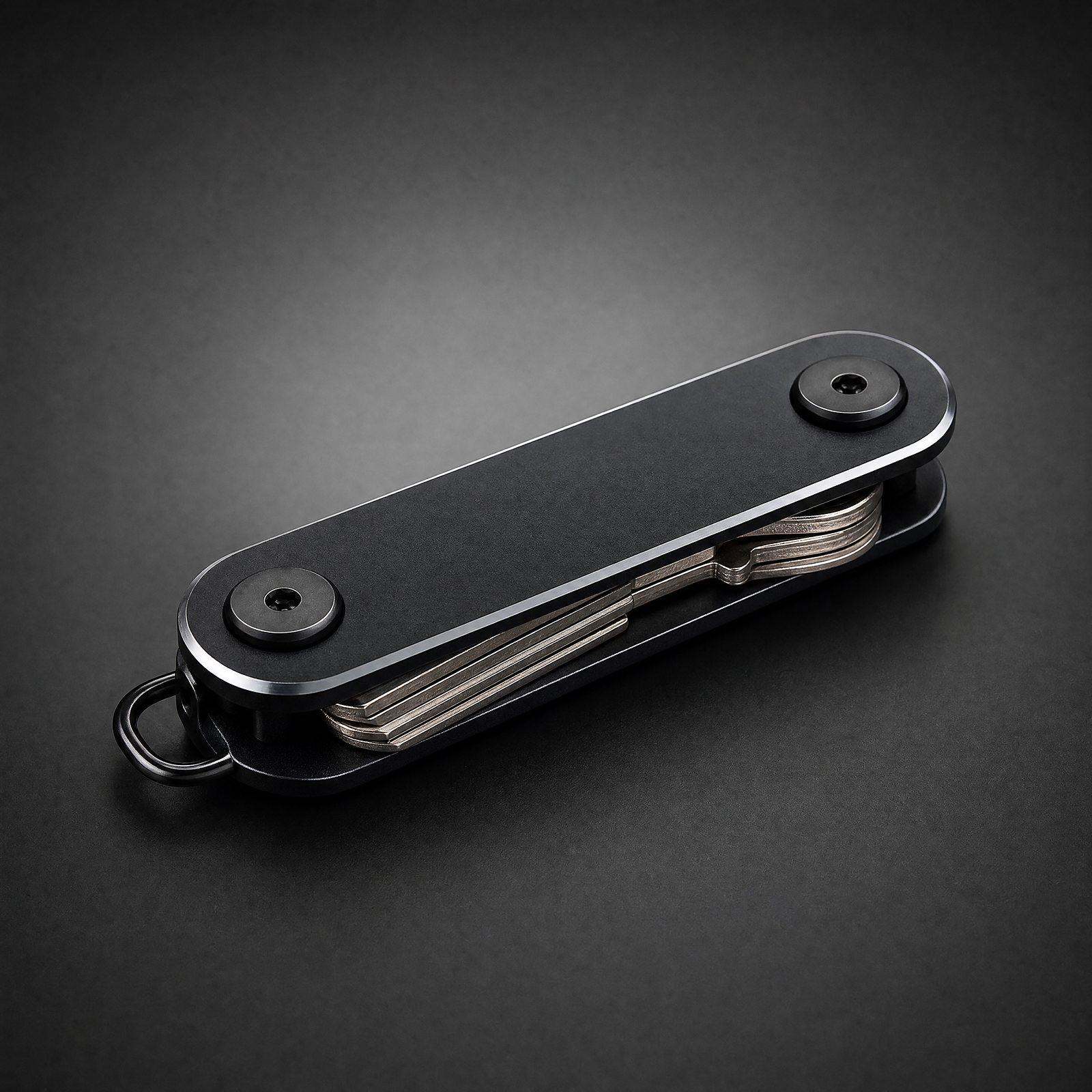 ANODE Key Organizer in matte black, closed with keys folded between the rails, three quarter view